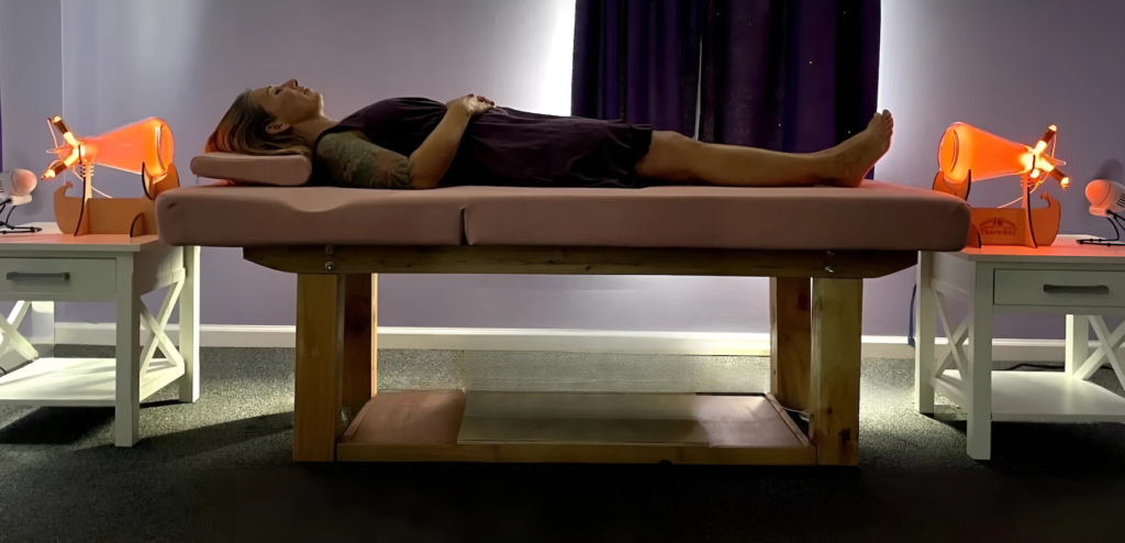 Woman laying on a table receiving a TheraPhi session. Haus of Life & Co
